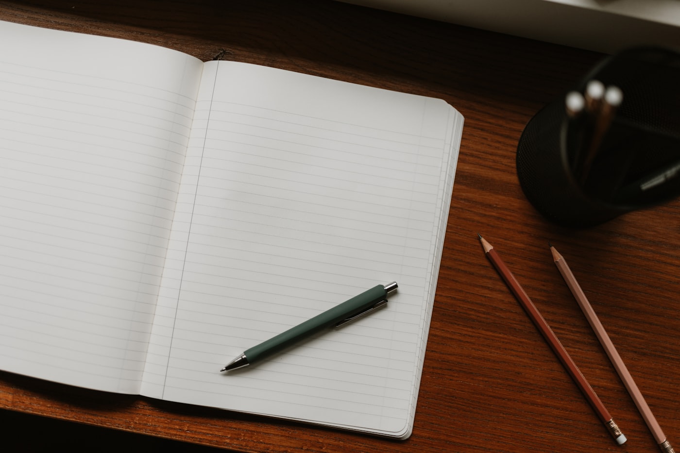 Schreibtisch mit offenem Notizbuch und Stift